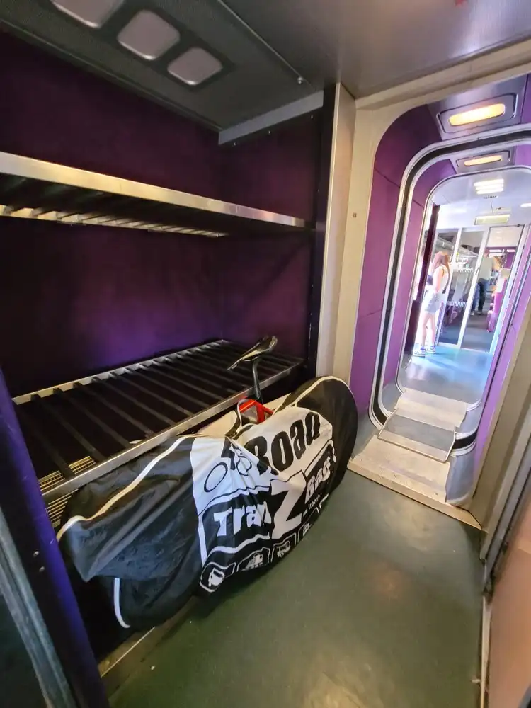 Packed bicycle in front of a luggage rack in a corridor