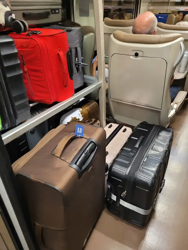 Small luggage rack with overflowing luggage in a Frecciarossa 1000 train